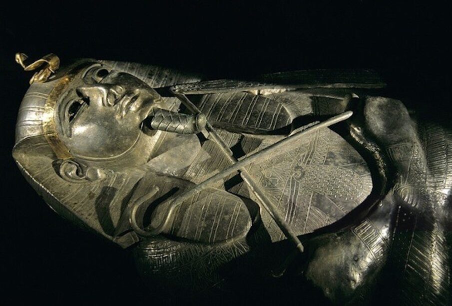 The coffin depicts Psusennes I holding the flail and the scepter.